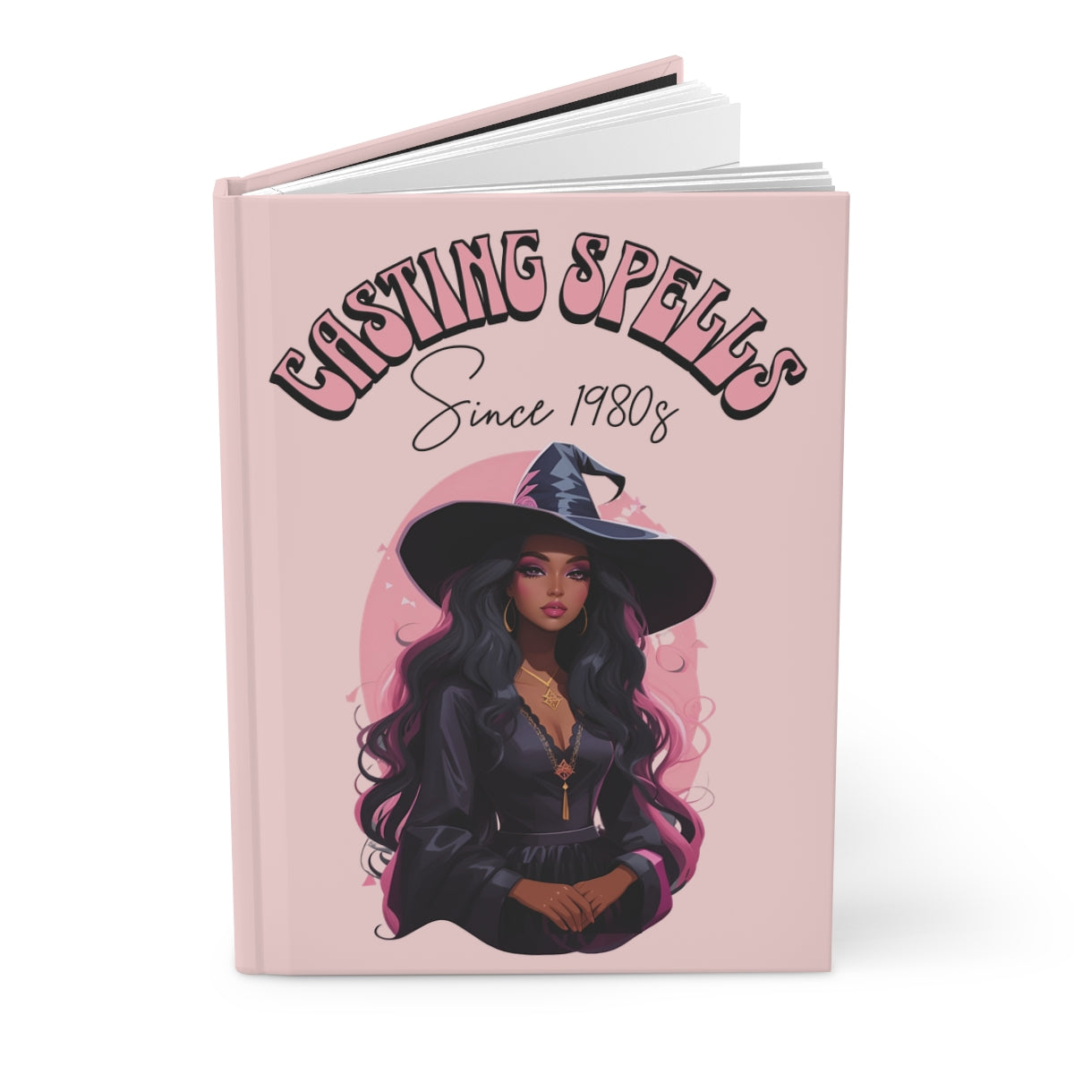 Baby pink notebook with a beautiful black witch girl illustration and 'Casting Spells Since 1980s' text written in retro groovy aesthetic font in pink