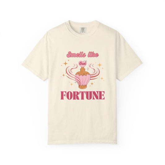 Beige t-shirt with a pastel pink retro style perfume bottle graphic and text 'Smells like Out of Fortune' 