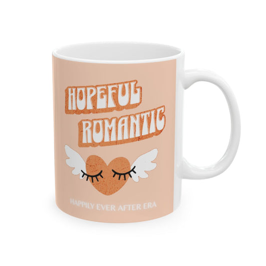 Mug with retro style 'Hopeful Romantic' text and an orange colored heart with wings on a peach background