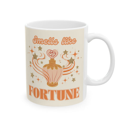 Mug with orange vintage style perfume bottle illustration surrounded by stars and an orange groovy style text 'Smells like Fortune' 